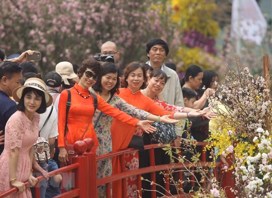Locals pose with cherry blossoms (Photo: VNA)