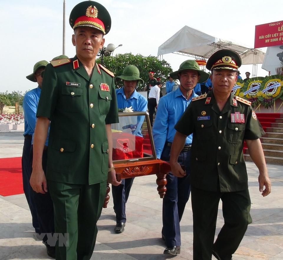 Local staff and army personnel carry the coffin containing a set of remain. (Photo: VNA)