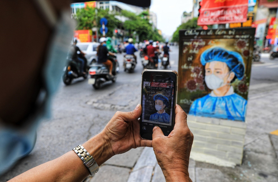 The poster on electric booth attracts a passer-by’s attention. (Photo: VNA) 