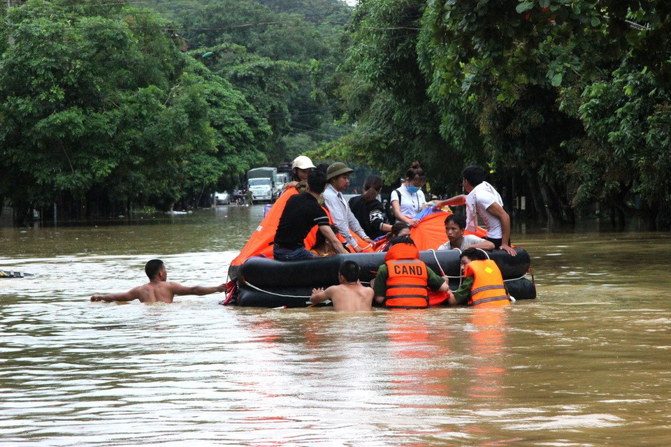 Soldiers and military officers are helping people cross a flooded street in the northernmost province of Ha Giang. (Photo: VNA)