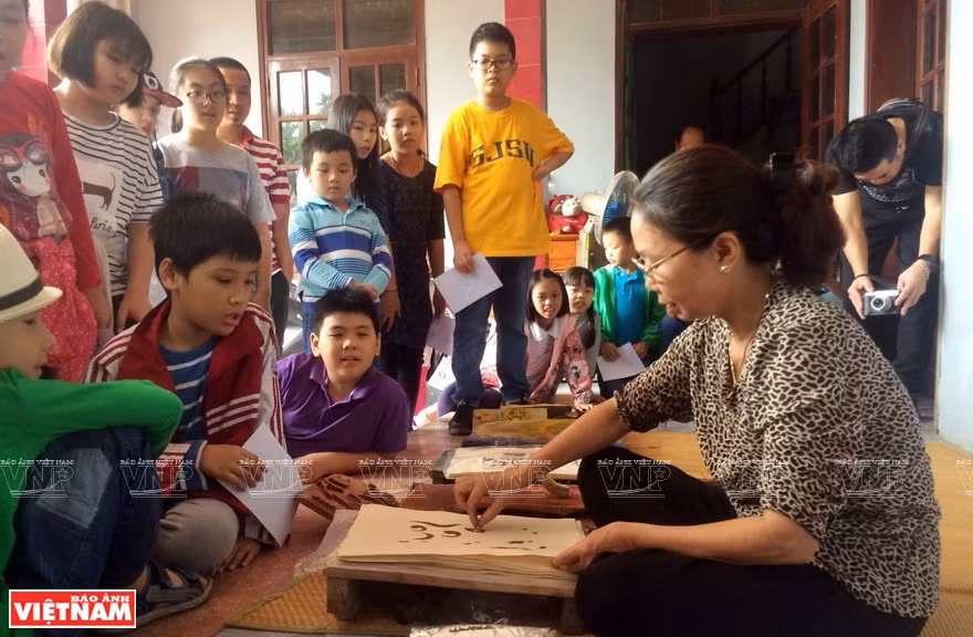 Artisan Nguyen Thi Oanh shows students how to make a Dong Ho painting (Photo:VNA)