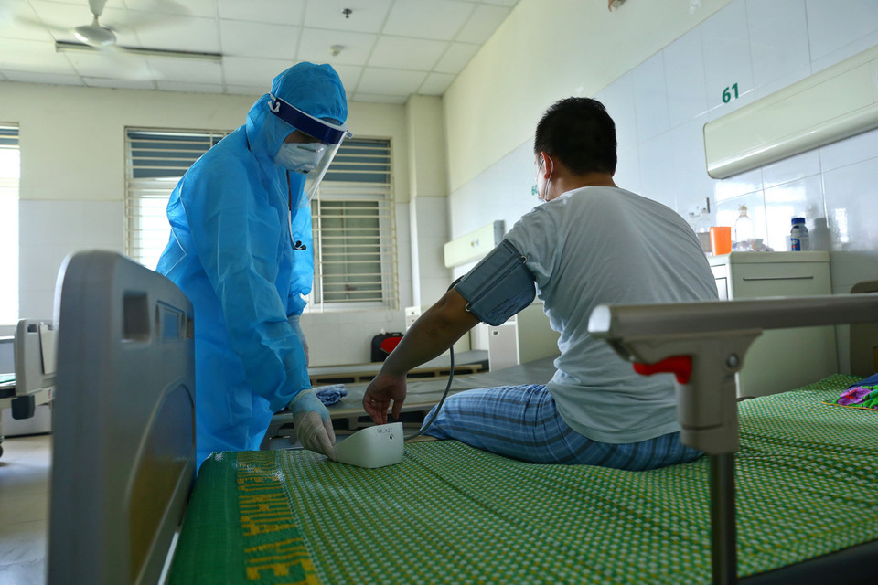 A doctor checks the health of a COVID-19 patient being treated at the National Hospital for Tropical Diseases, No.2, Dong Anh district, Hanoi (Photo: VNA)