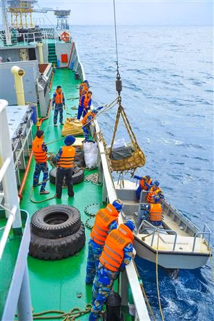 Officials, soldiers transport goods to the DK1/15 platform (Photo: VNA) 