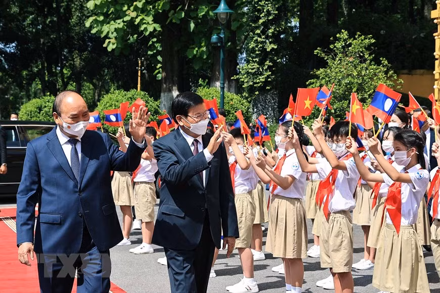 State President Nguyen Xuan Phuc and LPRP General Secretary and President of Laos Thongloun Sisoulith wave hands to children during the welcome ceremony in Hanoi. (Photo: VNA)