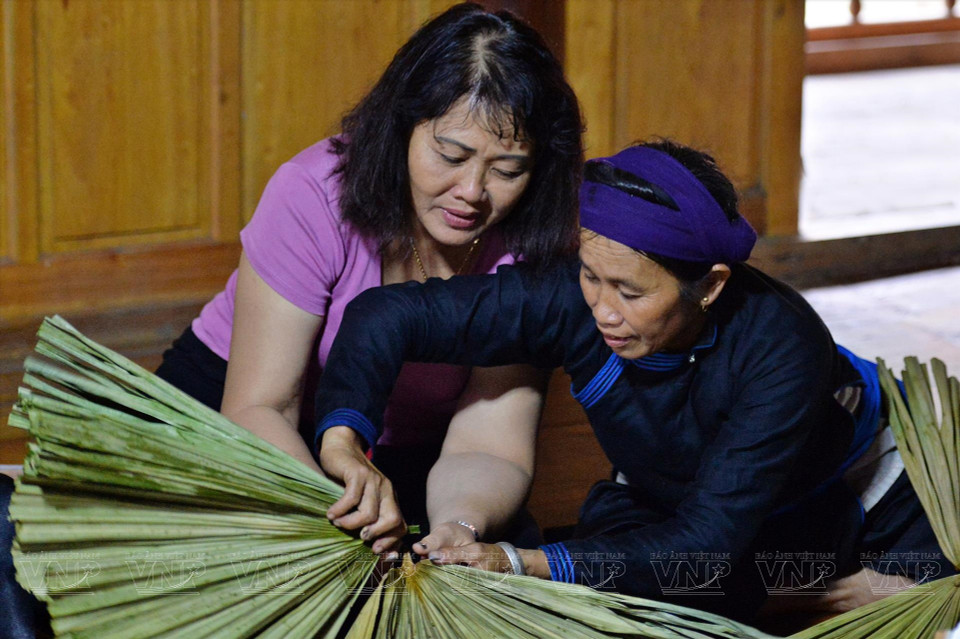 Tay ethnic women help tourists with the process of crafting palm-leaf hats. (Photo: VNP/VNA)