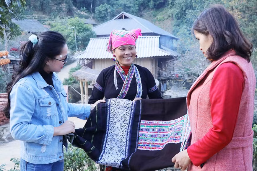 Lu ethnic woman showcases her brocade weaving product to tourists (Photo: VNA)