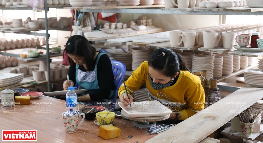 Craftspeople carefully draw decorative patterns on products. (Photo: VNP/VNA)
