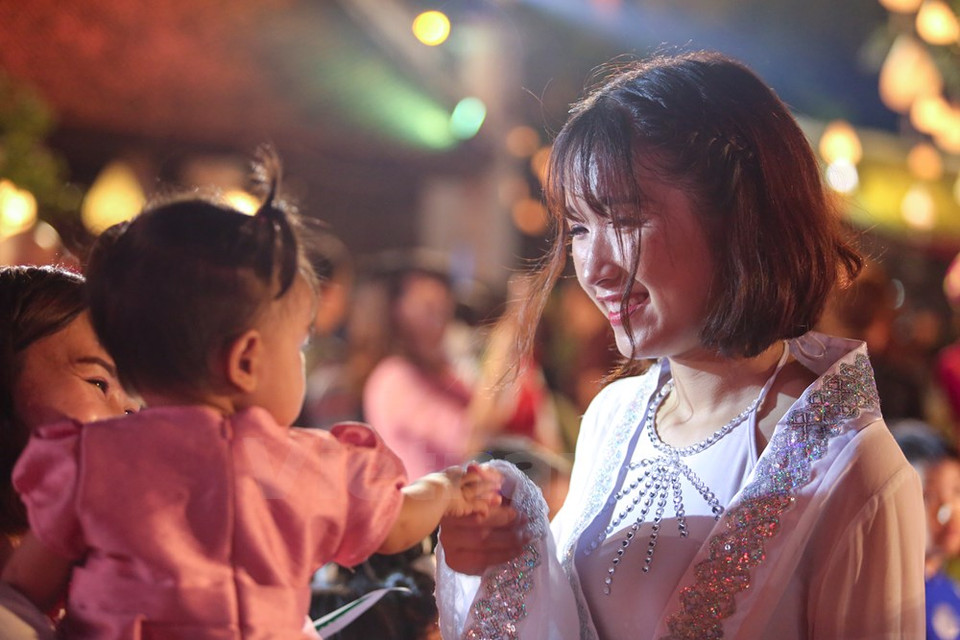 A girl, who acts as goddess of the Moon, at the festival, plays with a child (Photo: VNA)