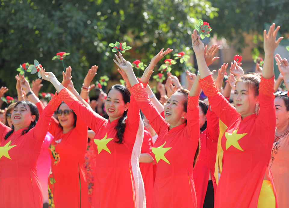 Women dressed in ao dai in the colours of the Vietnamese flag participate in the mass showcase. (Photo: VNP/VNA)