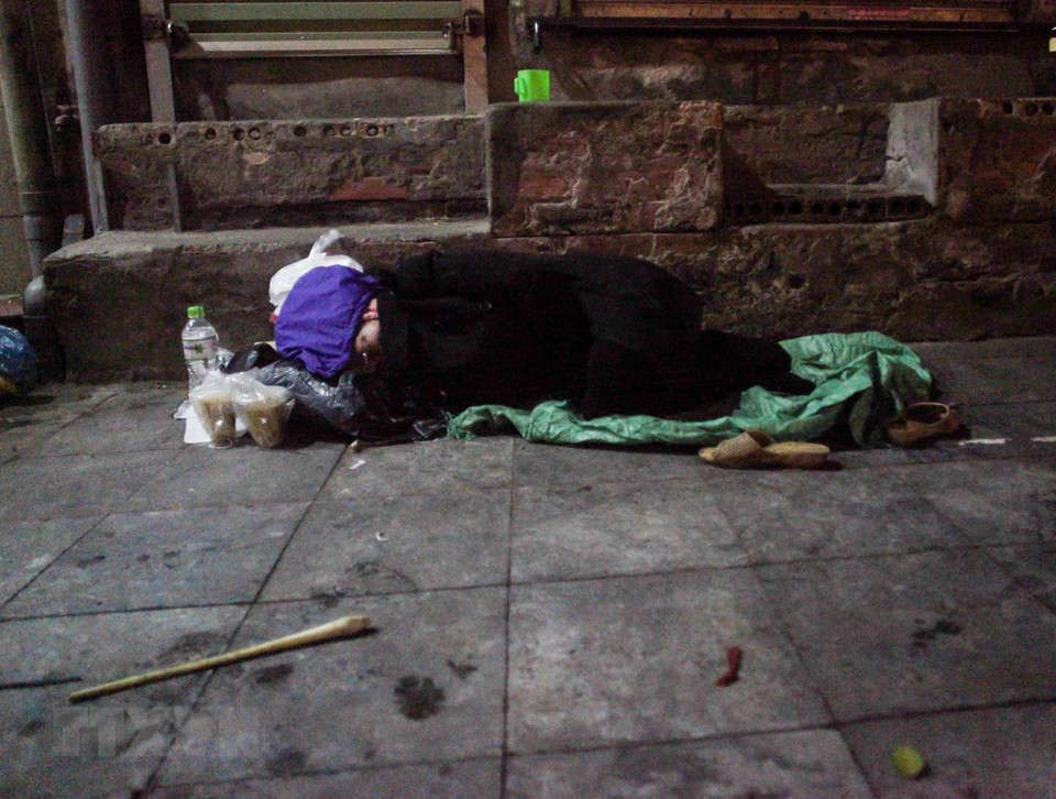 A homeless man huddles on a corner of Dong Xuan market in Hoan Kiem district, Hanoi (Photo: VNA)