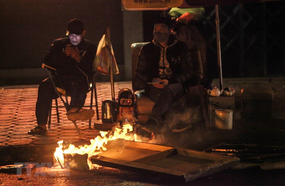 Manual labours on Hao Nam street, Dong Da district, set a fire to fight the frost (Photo: VNA)