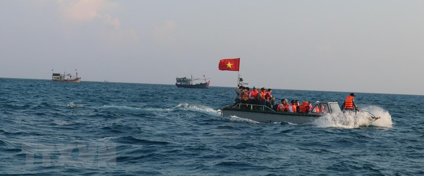 The motorboats of the Truong Sa 571 ship pass through the waters where Vietnamese fishing vessels are catching seafood near Da Tay A island. (Photo: VNA)