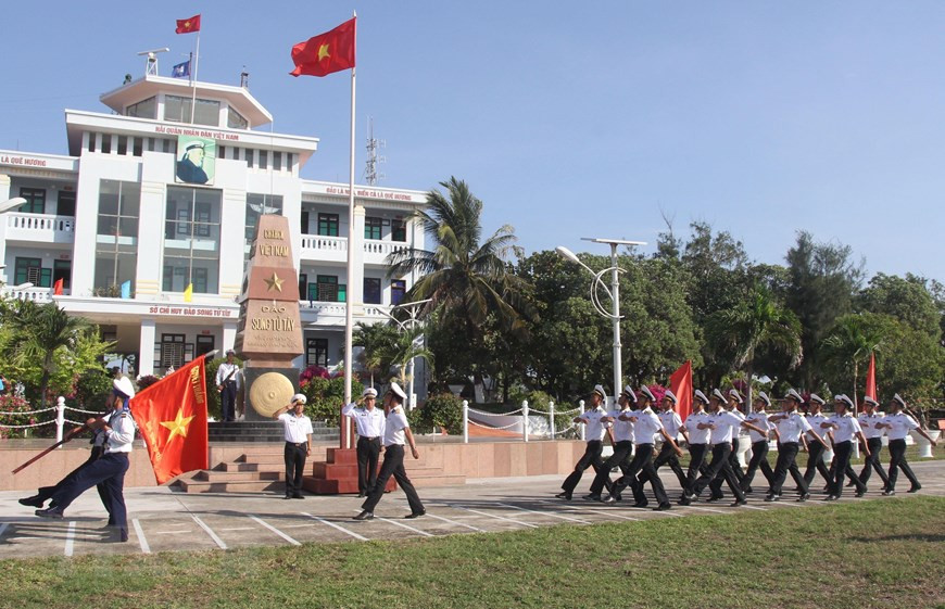 Guards carry the flag ‘Song Tu Tay island determined to win’ during a flag saluting ceremony on the island, April 28, 2021. (Photo: VNA)