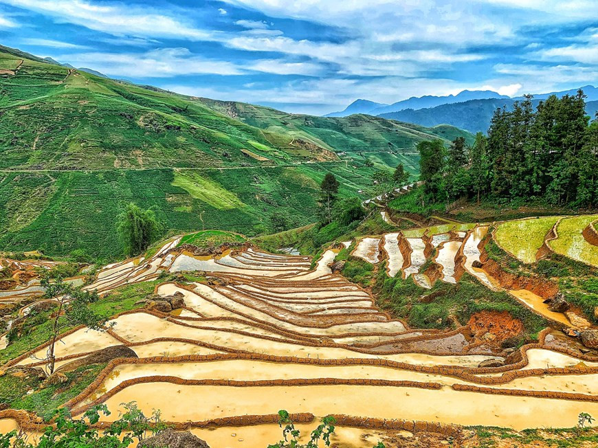 Y Ty, one of the poorest communes in Lao Cai province's Bat Xat district, has become an attractive tourism destination in recent years due to its natural beauty. Nestled against 2,700m Nhi Cu San mountain, the commune rarely sees the sun and is often covered by dense white clouds. Leaving Lao Cai train station and driving the 70km to Bat Xat along mountainous roads that stretch like wild snakes, you will reach this foggy land, 2,000m above sea level. From the car windows, you can see zigzag tracks sunk deep in forest leaves and houses that appear and disappear in the clouds. Y Ty attracts tourists by the clouds, mountains, and artistic terraced rice fields (Photo: Vietnamplus) 