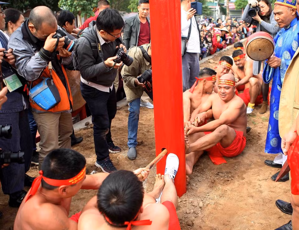 Two teams sit on the ground and tug a rope over 30 metres long that is passed through a hole in a wooden pole fixed firmly in the ground (Photo: Thanh Tung/VNA)