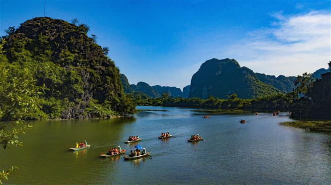Tourists travel on boat along Ngo Dong river to enjoy the magnificent caves. (Photo: VNA)