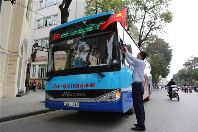 A bus driver hangs a national flag on his bus (Source: VNA)