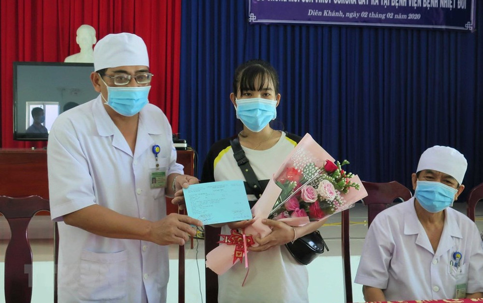 Deputy Director of Khanh Hoa Hospital of Tropical Diseases Nguyen Vu Quoc Binh presents flowers and hospital discharge certificate for patient Le Thi Thu H who recovered from disease caused nCoV after treatment (Photo: VNA)