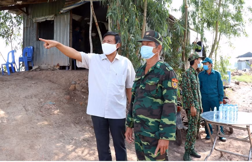 Vo Anh Huy, Permanent Deputy Secretary of the Duc Hue District's Party Committee, Long An province (left) exchanges the situation of epidemic prevention with soldiers of an epidemic prevention post (Photo: VNA)