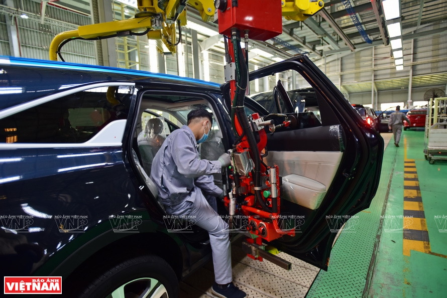 A worker uses robotic technology to assemble auto doors. (Photo: VNA)