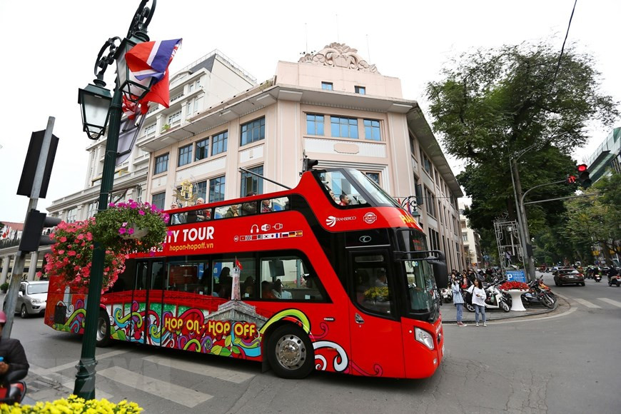 Many tourists go for double decker to enjoy the bustling atmospheres on Hanoi’s streets as the summit is nearing (Photo: VNA)