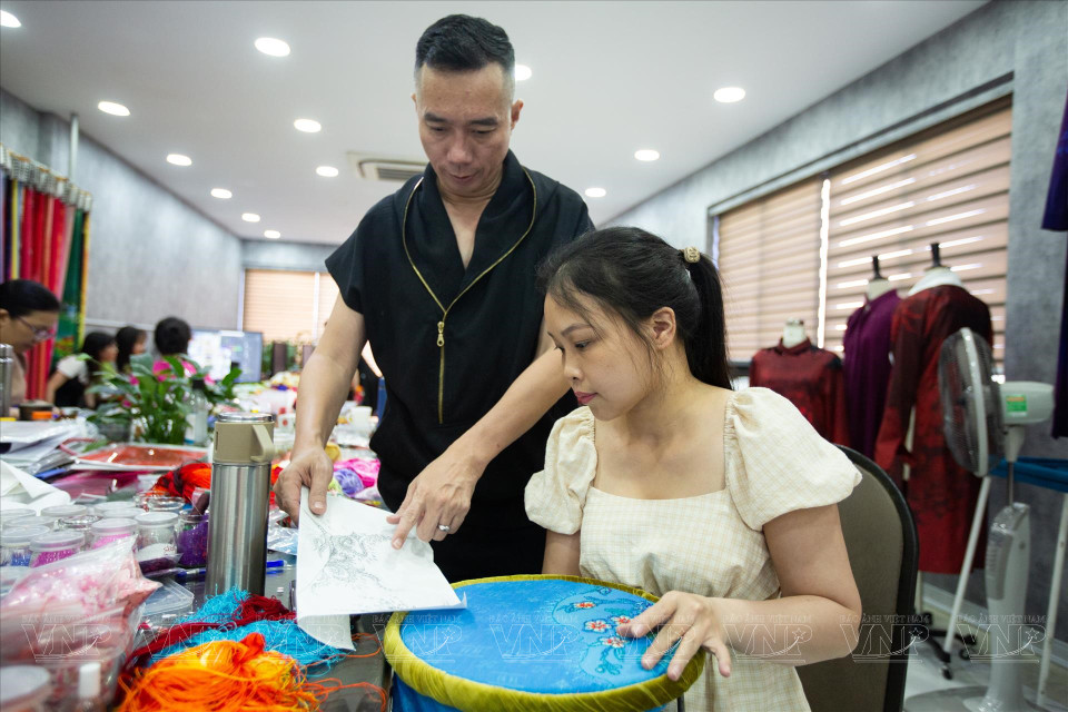 Designer Do Trinh Hoai Nam shows an employee how to attach patterns to fabric. (Photo: VNP/VNA)