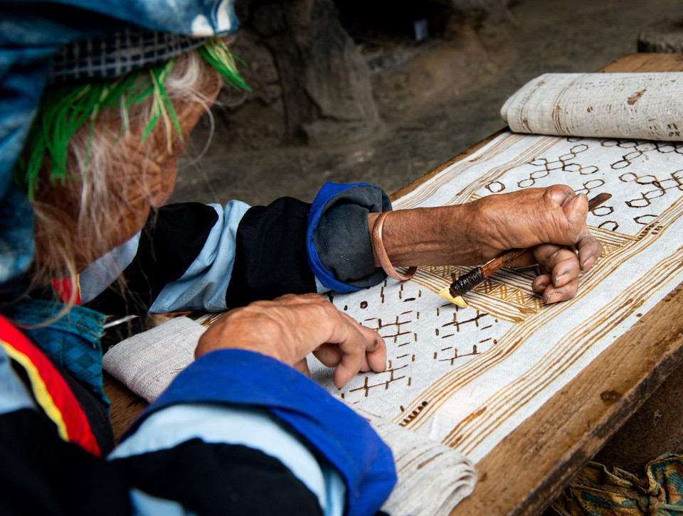 What makes the Mong-made flax clothing distinguishable from others is the sophisticated brocade patterns and the beeswax drawing. The craftswomen use heated beeswax to paint traditional decorative patterns of the Mong people on the sheets. (Photo: VNA)