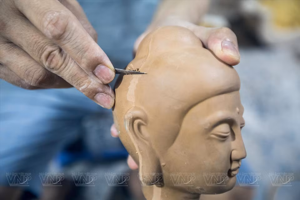 Carving carefully to make the Buddha image close to everyday life. (Photo: VNP)