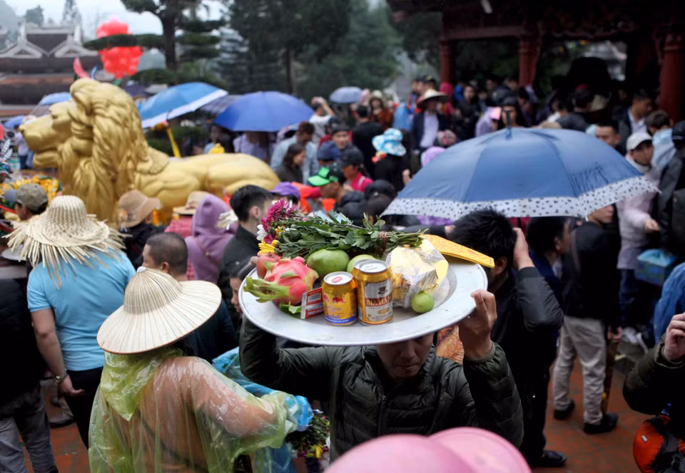 A man raises a tray of offerings to get through the crowd at the Huong Pagoda Festival, which is one of the longest festivals in Vietnam when it lasts through the third lunar month (Photo: VNA)