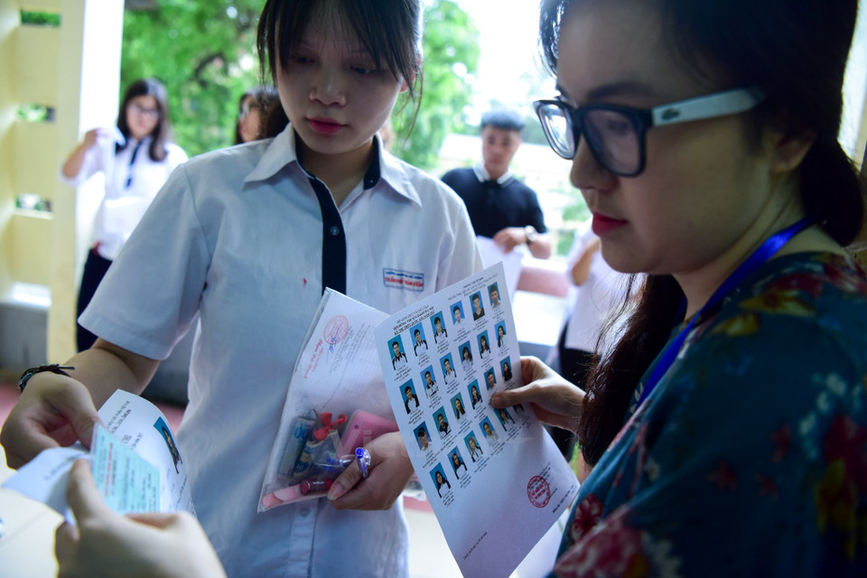 A proctor checks personal cards of an examinee before the student enters the test room (Photo: VNA)