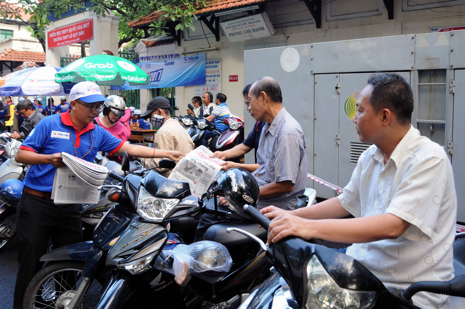 Voluntary university students distribute free newspapers to relatives of examinees outside the Le Quy Don High School in District 3 of Ho Chi Minh City (Photo: VNA)