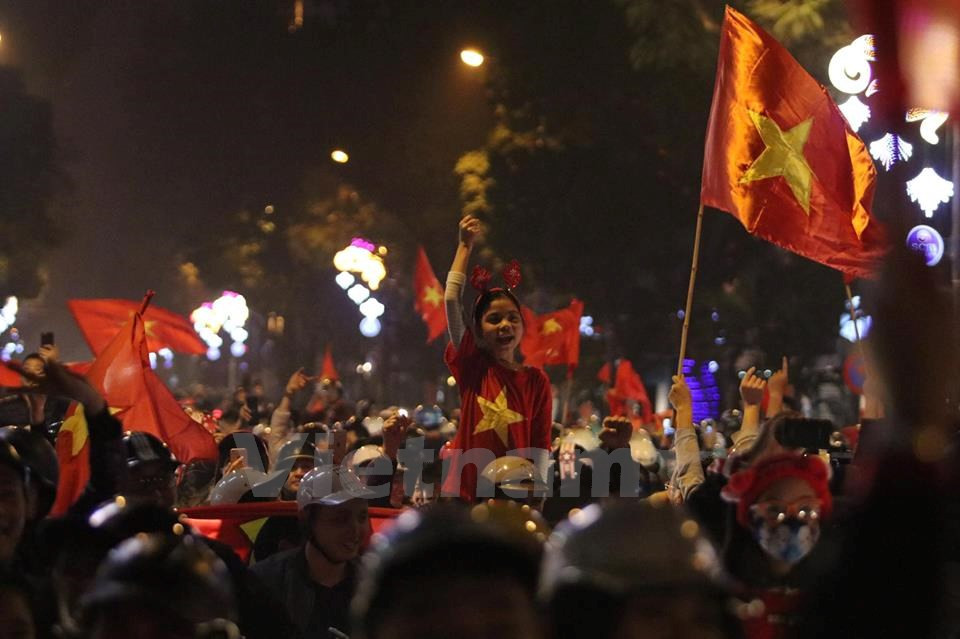 Football lovers in Hanoi celebrate the win together with the national flag (Photo: VNA)
