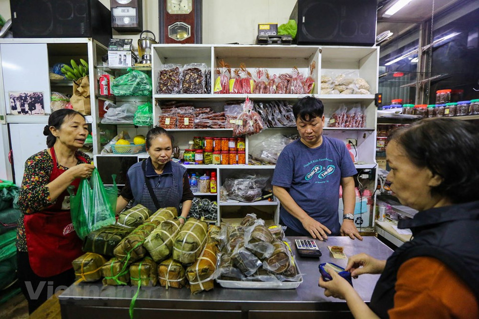 The bustling atmosphere is a daily thing in Quoc Huong shop. During the last days of the lunar year, from the Kitchen God Day onwards, the store staff do not have time to eat, drink water, work tirelessly to cook, pack, answer the phone, arrange orders ... Hundreds of square glutinous rice cakes come out in each batch. Quoc Huong shop does not set a rate for customers to buy only a certain quantity of product, but sells as many as they want. However, not all customers can buy all the things they need in one queue, because goods are often sold out very quickly. (Photo: Vietnam+) 