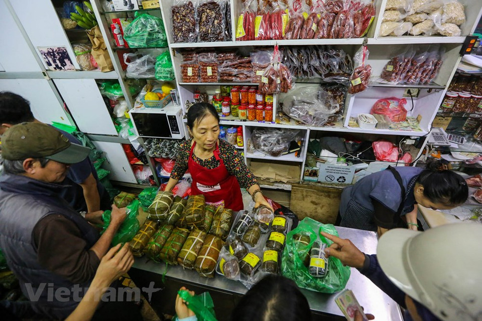 People have to make their way through the crowd to buy a pair of cakes. Each batch of goods include hundreds of banh chung, but in only one hour, all were sold out. After an hour in line, those who bought it in time would happily take out the ‘spoils’ to leave, those who could not buy in time had to wait eagerly for the next batch of goods which may come in a few hours later. It was hard, but many people still queue around at the store until they can buy products. Perhaps, the harder the work is, the greater the joy of buying a pair of famous banh chung, good and famous pork pies, ad the more delicious Tet meal. (Photo: Vietnam+) 
