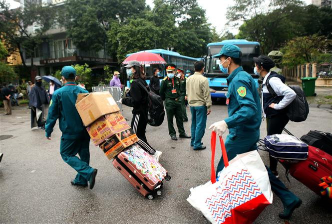 Militiamen help people finishing their quarantine time with their luggage (Photo: VNA)