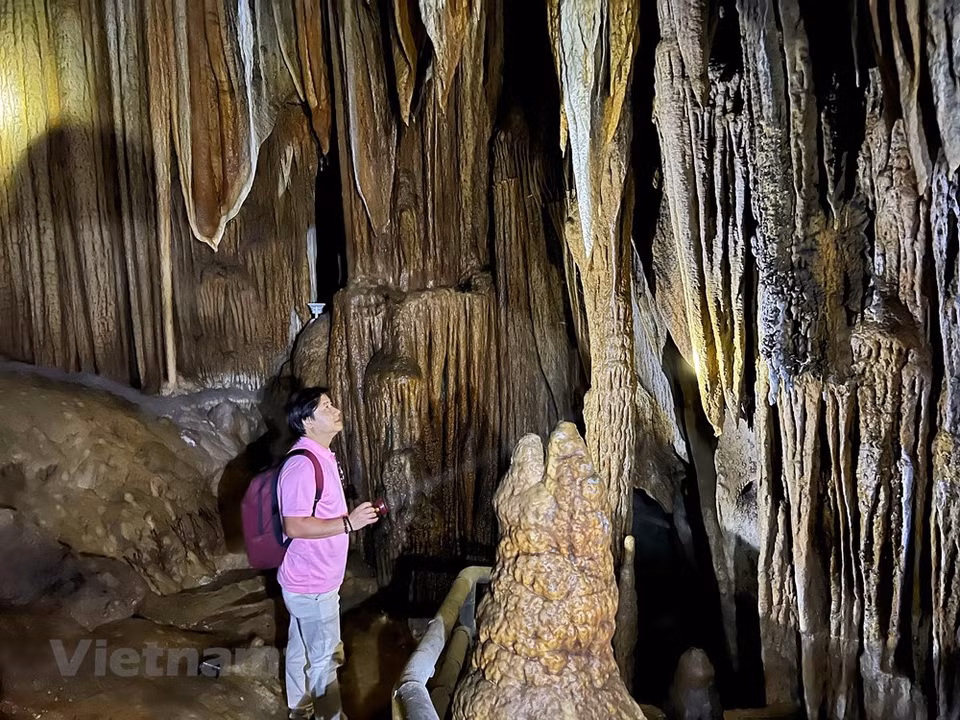 Stepping through the gate which is only one metre in height, visitors will be surprised as if they enter a new world. The cave has a dark and cool atmosphere. Stalactites and stalagmites have vivid shapes and seem to hold the feet in place. Sometimes they look like the curtains of a castle, sometimes like a silk strips hanging from the cliff. There are winding stone veins in the cave walls that look like they were installed by a painstaking and skilled craftsman. There are many stalactites like silk strips on the cave walls. Visitors can see water flowing from the mountain, forming small geysers along the cliffs. They are very unique, sometimes like a small waterfall, sometimes like the mouth of a large river. (Photo: VietnamPlus)