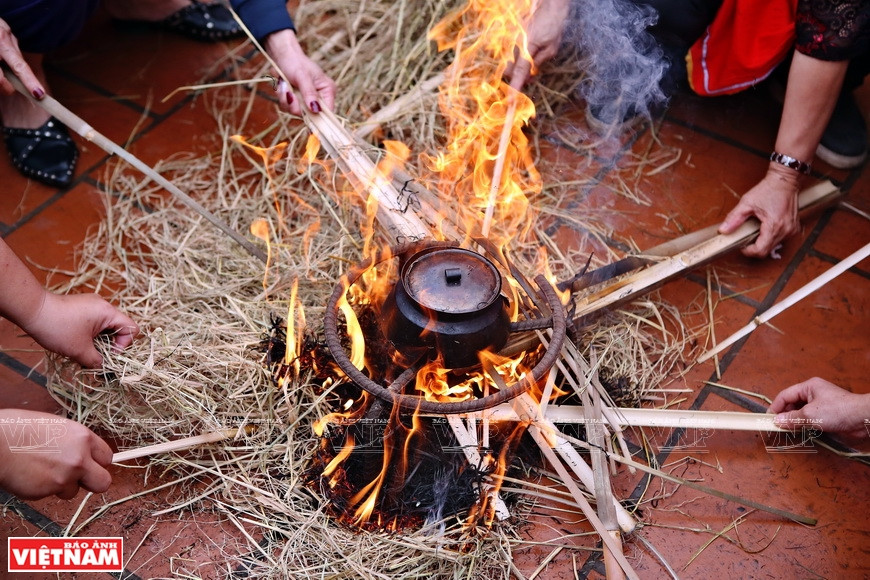 The rice pot is kept surrounded by burning straw (Photo: VNA)