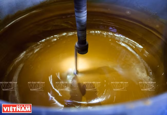 Stirring the liquid sugar by machine. (Photo: VNA)