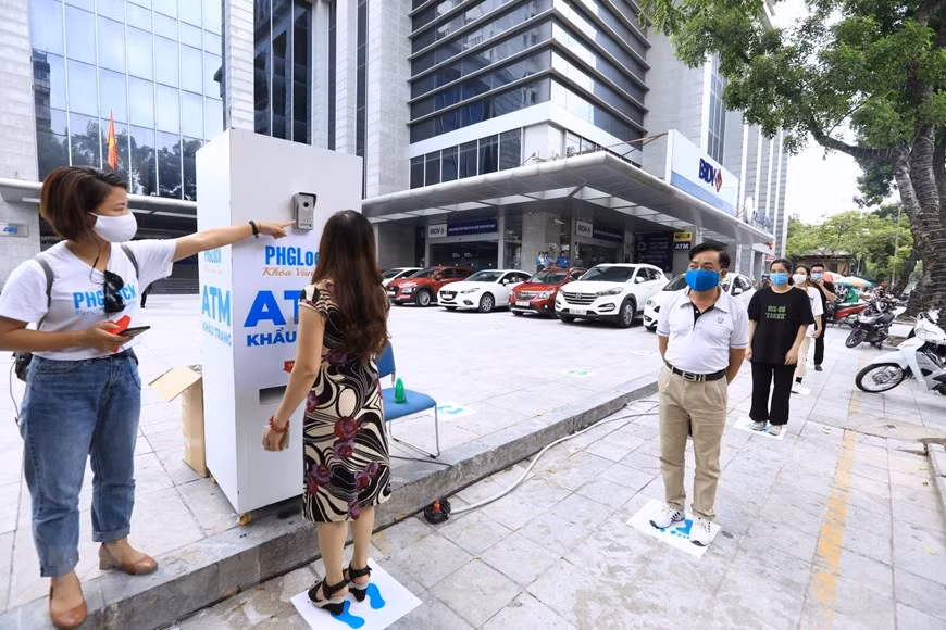 Ahead of receiving the masks, citizens are required to line up and keep a minimum distance of two metres (Photo: VNA)