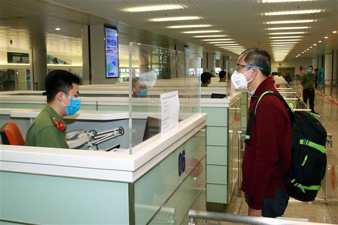 A border gate policeman checks the passport of a passenger on entry at Noi Bai International Airport (Photo: VNA)
