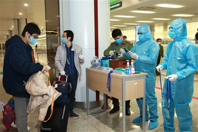 Border gate police at Noi Bai International Airport check passengers’ passports, give instructions and cards to passengers subject to isolation (Photo: VNA)