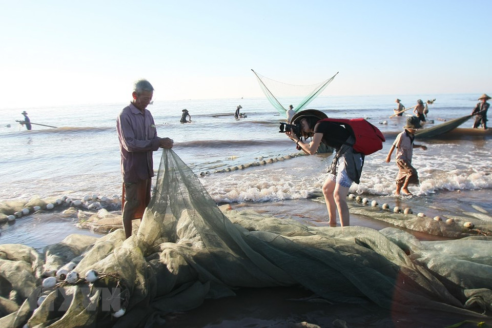 A VNA journalist photographs a fisherman in Hai Ly commune, Hai Hau district, Nam Dinh province (Photo: VNA)