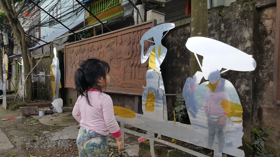 A recreation of Hanoi feudal life features a carved painting and nicely cut human shapes made of metal (Photo: VNA)