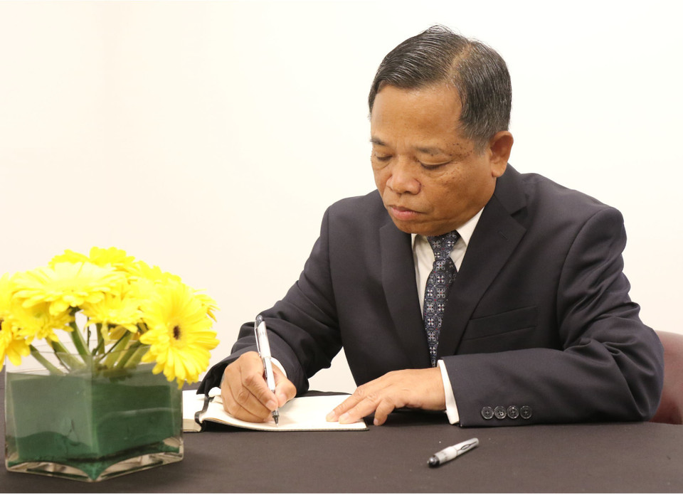 Ambassador Khiane Phansourivon, head of the Lao Permanent Mission to the UN, writes on the book of condolences. (Photo: VNA)