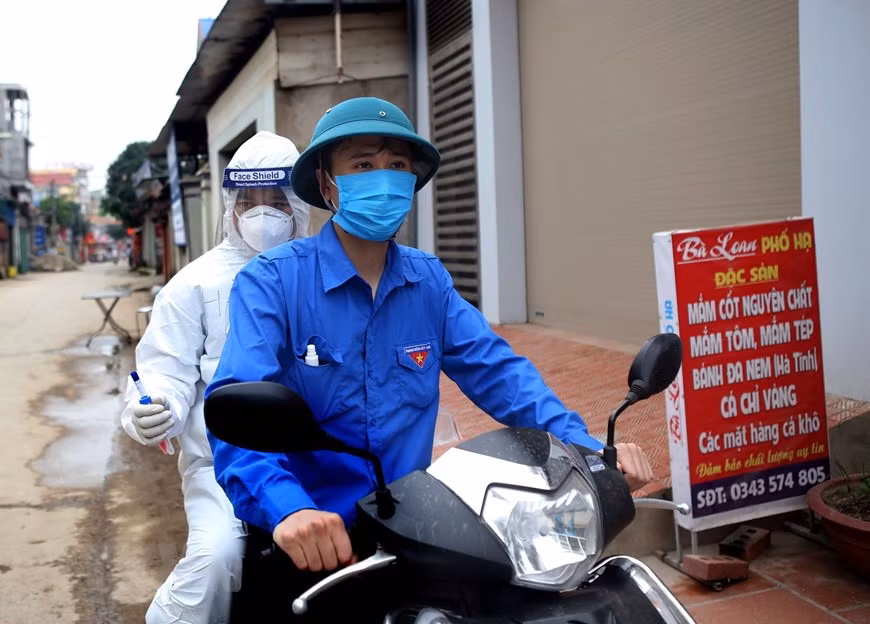 A local resident in Ha Loi hamlet supports a medical worker by giving him a ride (Photo: VNA)