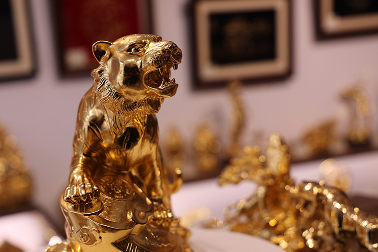 It takes days of detailed work for artisans to make a gold-plated figurine. The process requires painting, gilding, and polishing the model, which often starts with clay, then ending with a copper sculpture before being plated with the precious metal. (Photo: Tintuc/TTXVN)