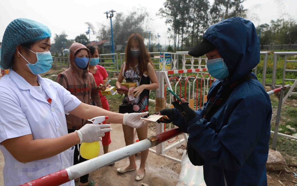 A medical staff in Son Loi commune disinfects money before payment (Photo: VNA)