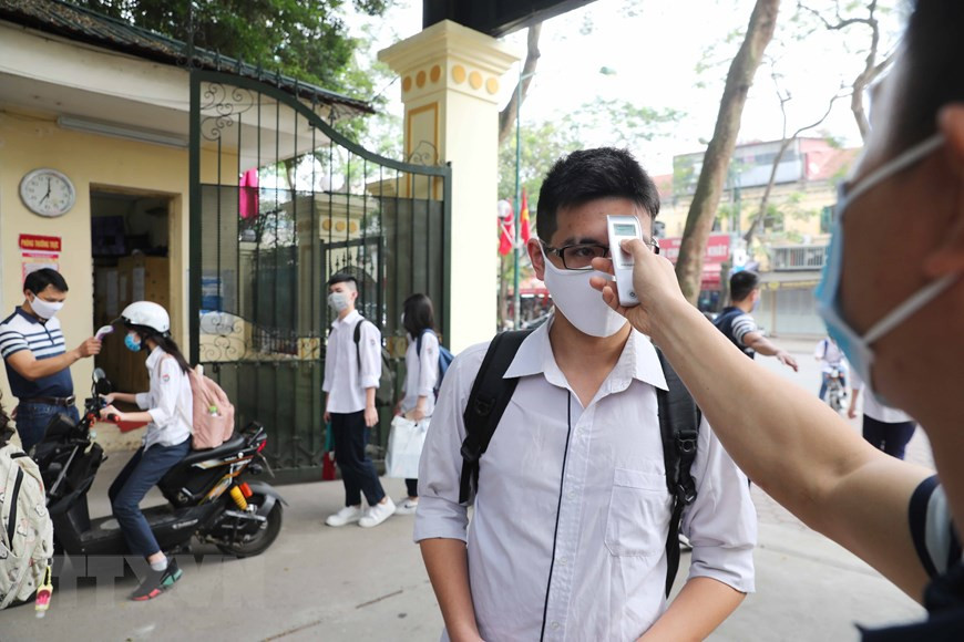 All teachers and students are required to go under body temperature measurement before entering the school (Photo: VNA)