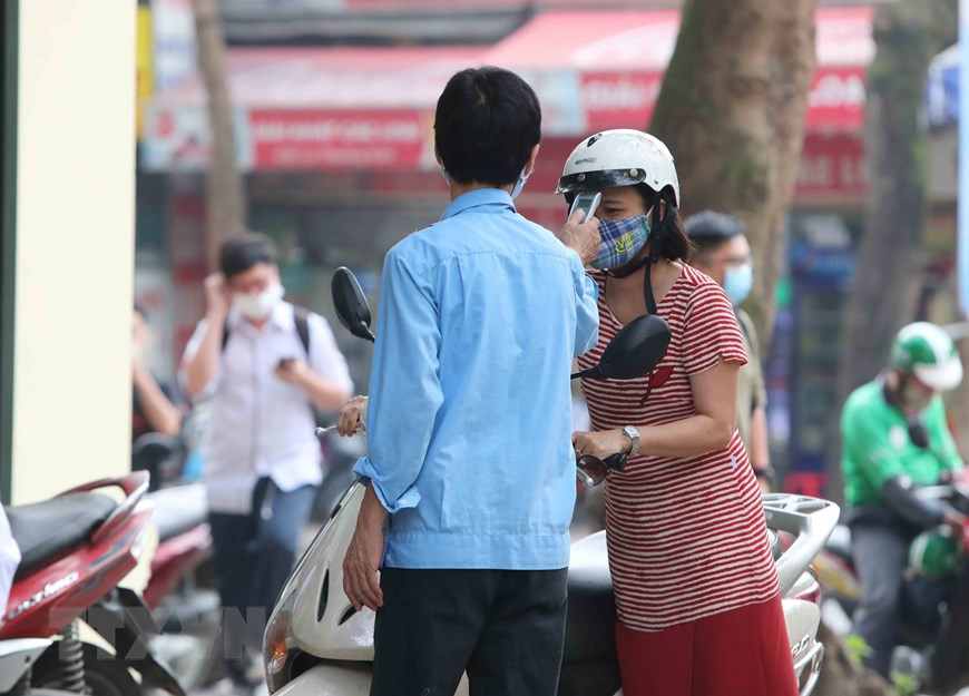 Body temperature of all teachers and students are measured before they enter the school (Photo: VNA)