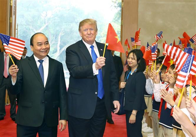 Prime Minister Nguyen Xuan Phuc and US President Donald Trump wave Vietnamese and US flags together with children in Hanoi, February 27, 2019 (Photo: VNA)